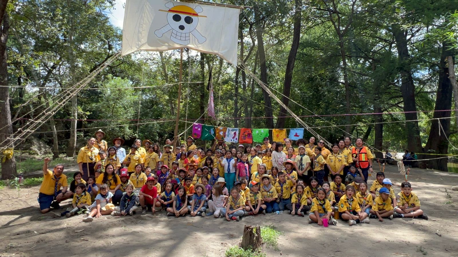 Manada de lobatos reunida bajo un mástil en campamento